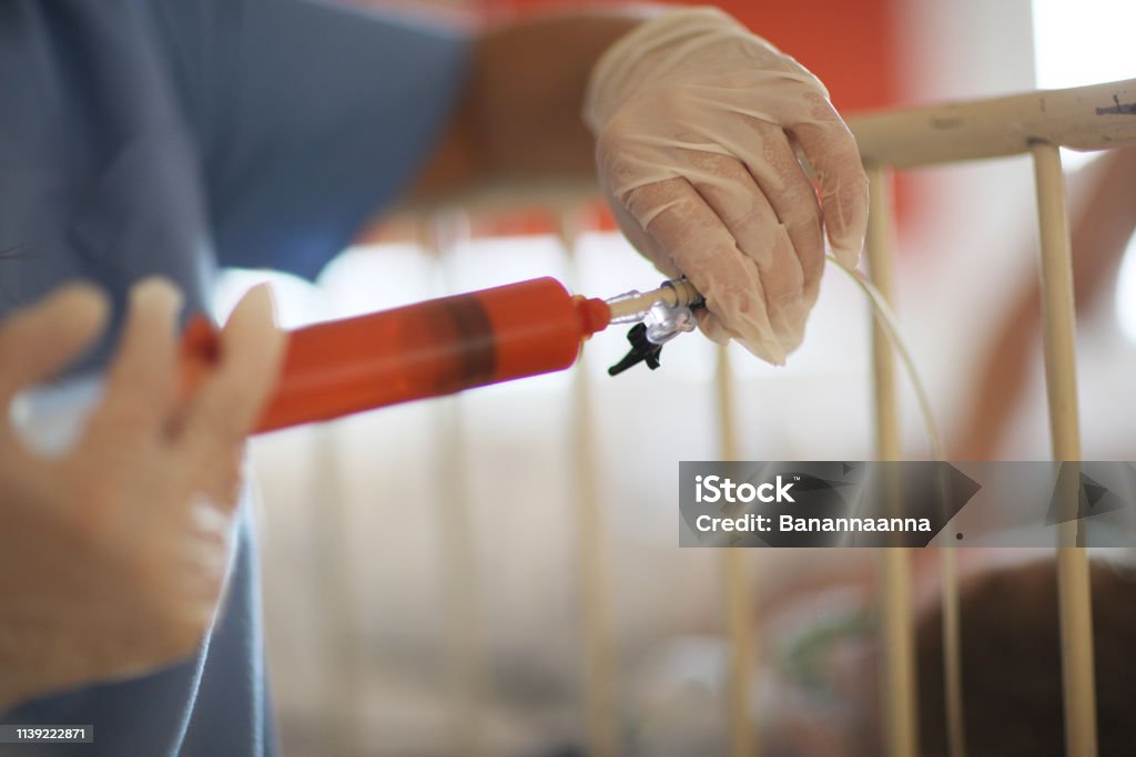 Nurse Injects Medication The nurse injects the medication into the infusion tube Medicine Stock Photo