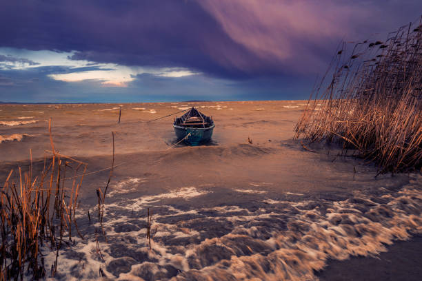 Fishing boat on a lake on a windy day during a storm tied up to the shore stock photo