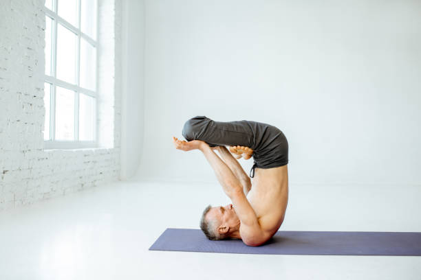 istock Senior man practising yoga indoors 1139227548