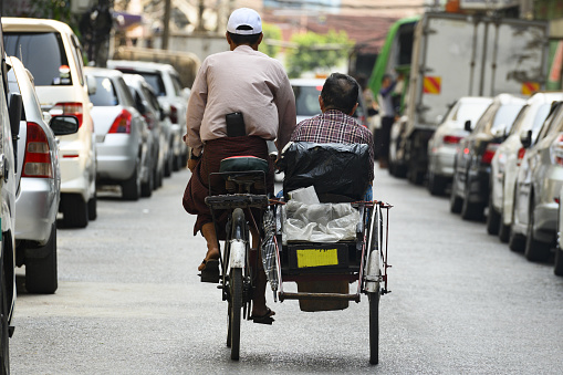 Yangon, Myanmar, March 17, 2019. A unidentified Sai Kaa driver is carrying a passenger on his side car among the narrow streets of Yangon, Myanmar. The Sai Kaa rickshaw is a type of tricycle designed to carry passengers on for hire basis and is widely used in southeast Asia.