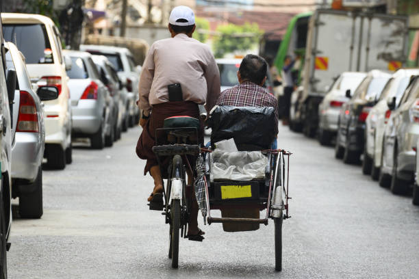 A unidentified Sai Kaa driver is carrying a passenger on his side car among the narrow streets of Yangon, Myanmar. Yangon, Myanmar, March 17, 2019. A unidentified Sai Kaa driver is carrying a passenger on his side car among the narrow streets of Yangon, Myanmar. The Sai Kaa rickshaw is a type of tricycle designed to carry passengers on for hire basis and is widely used in southeast Asia. philippines tricycle stock pictures, royalty-free photos & images