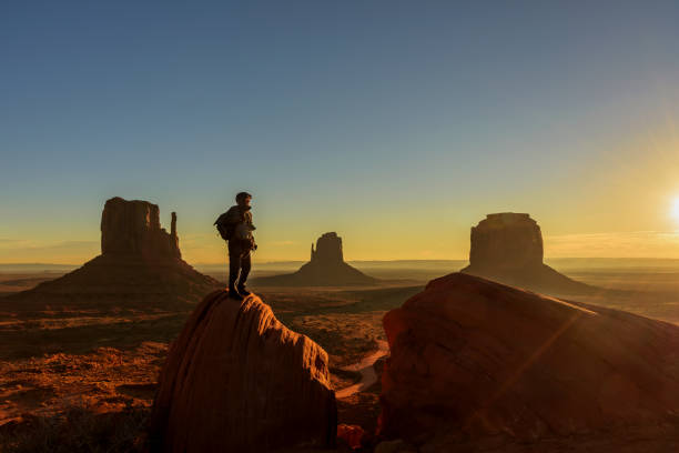 a traveller admiring sunrise at monument valley, arizona - monument valley usa panoramic imagens e fotografias de stock