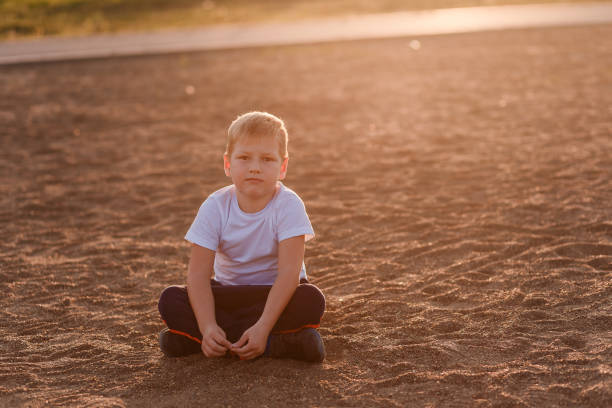 istock boy in a white t-shirt sits on the sand 1139248700
