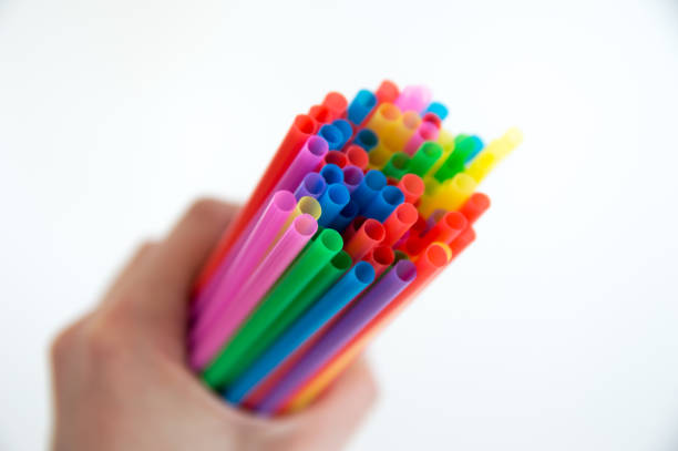 istock Multicolored plastic tubes for a cocktail in hand on a white background. Polymers in everyday life. 1139262870