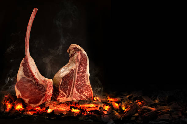 Whole T-Bone steak cooking on embers. Black background. Whole T-Bone steak cooking on embers. Black background. Space for text t bone steak stock pictures, royalty-free photos & images