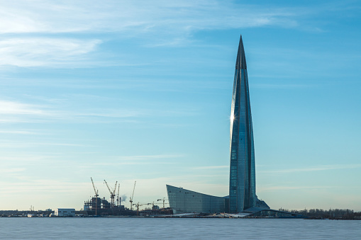 The Lahta center skyscraper buidling on the shore of Finish bay covered with ice and snow near Petersburg city in the mouth of Neva river in the clear day