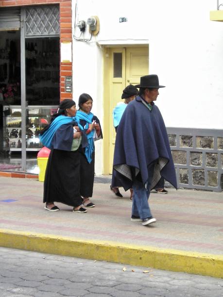 Walkng Down the Street September 24th, 2003.  Cordillera Oriental, Andes, Ecuador.  Three women and a man are walking down a street.  The women are wearing long skirts and shawls, the man is wearing a poncho and hat. mcdermp stock pictures, royalty-free photos & images