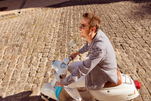 istock Handsome cheerful man with glasses riding a scooter 1139269625