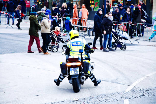 Dortmunder Rosenmontag on Kampstrasse: German police officer and patrol motorcycle after a colourful Dortmund Germany Rose Monday parade German police officer and patrol motorcycle after a colourful Dortmund Germany Rose Monday parade - highlight of the German Karneval, held on the Shrove Monday before Ash Wednesday.
 Rosenmontag is celebrated heavily in German carnival strongholds which include the Rhineland, especially in Cologne, Bonn, Düsseldorf, Aachen and Mainz riot police stock pictures, royalty-free photos & images