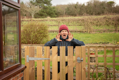 Annoyed mature woman shouting over fence