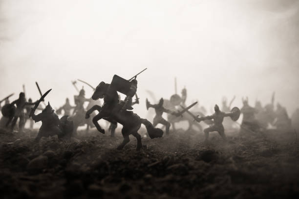 istock Medieval battle scene with cavalry and infantry. Silhouettes of figures as separate objects, fight between warriors on sunset foggy background. Selective focus 1139285879