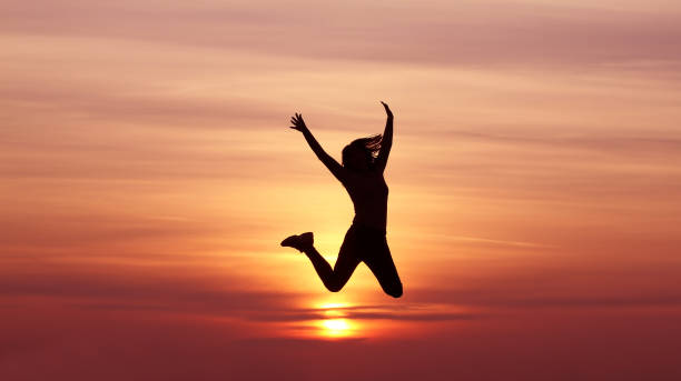 istock Silhouette girl jumping at sunset 1139288465