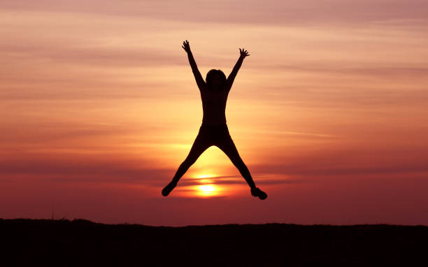 istock Silhouette girl jumping at sunset 1139289057