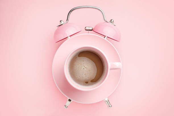pink alarm clock and coffee cup on pink background. breakfast time concept. minimal style - wakening imagens e fotografias de stock