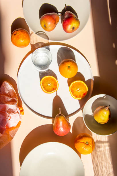 istock Pears and oranges with  art shadows on a color backround. Artistic healthy breakfast on a table. 1139294653