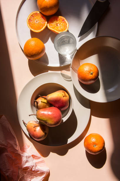 istock Pears and oranges with  art shadows on a color backround. Artistic healthy breakfast on a table. 1139295278