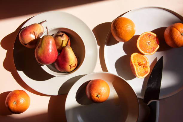 istock Pears and oranges with  art shadows on a color backround. Artistic healthy breakfast on a table. 1139295363