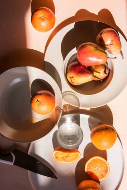 istock Pears and oranges with  art shadows on a color backround. Artistic healthy breakfast on a table. 1139295432