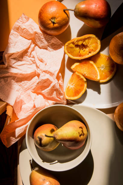 istock Pears and oranges with  art shadows on a color backround. Artistic healthy breakfast on a table. 1139295538