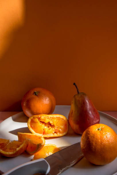 istock Pears and oranges with  art shadows on a color backround. Artistic healthy breakfast on a table. 1139295609