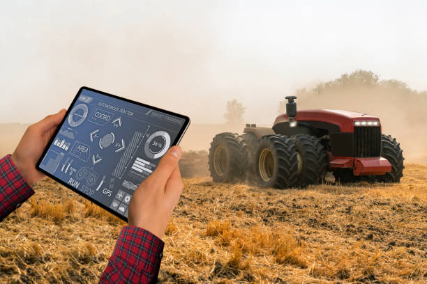 デジタルタブレットを持つ農家は、自律トラクターを制御します - 遠隔操作 ストックフォトと画像