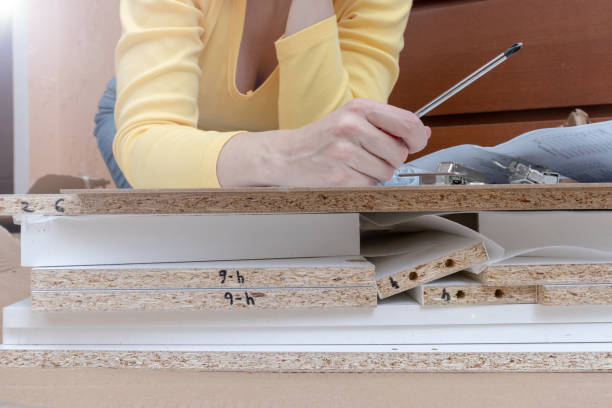 istock Woman sitting on the floor at home and assembling furniture using hand tools 1139312701