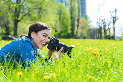 Girl photographer taking pictures on nature flowers