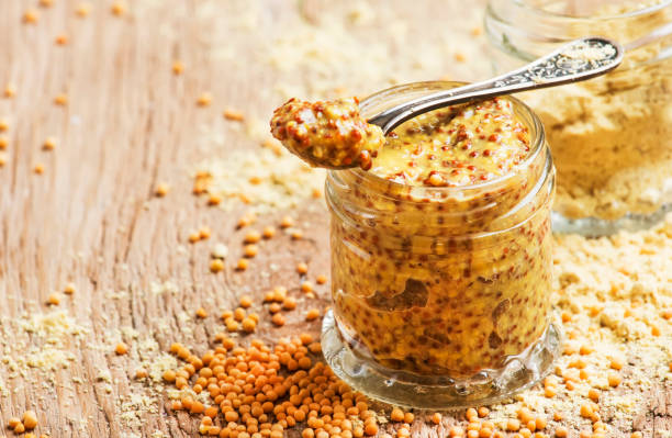 Mustard with grains, ready hot sauce, old wooden kitchen table, selective focus Mustard with grains, ready hot sauce, old wooden kitchen table, selective focus dijon stock pictures, royalty-free photos & images
