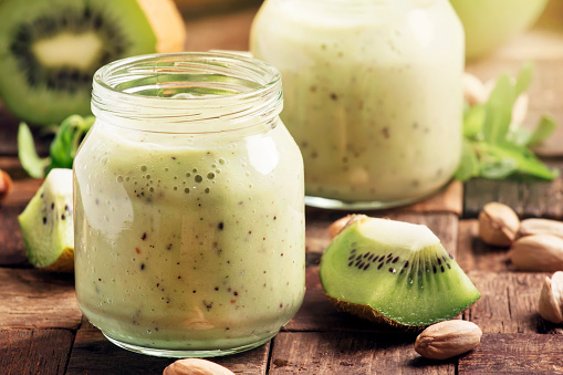 Smoothie with banana, kiwi and nuts, old wooden background, selective focus
