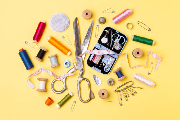 istock Composition with threads and sewing accessories - scissors, centimeter, pins on yellow background. 1139327070
