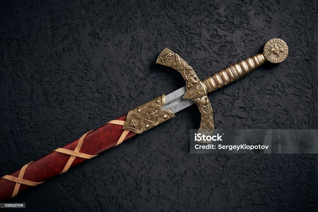 Ancient knightly sword of the era of the Crusades Ancient knightly sword of the era of the Crusades in the Middle Ages, the Knights Templar against a dark background. Sword Stock Photo
