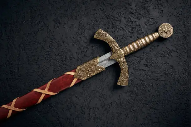 Ancient knightly sword of the era of the Crusades in the Middle Ages, the Knights Templar against a dark background.