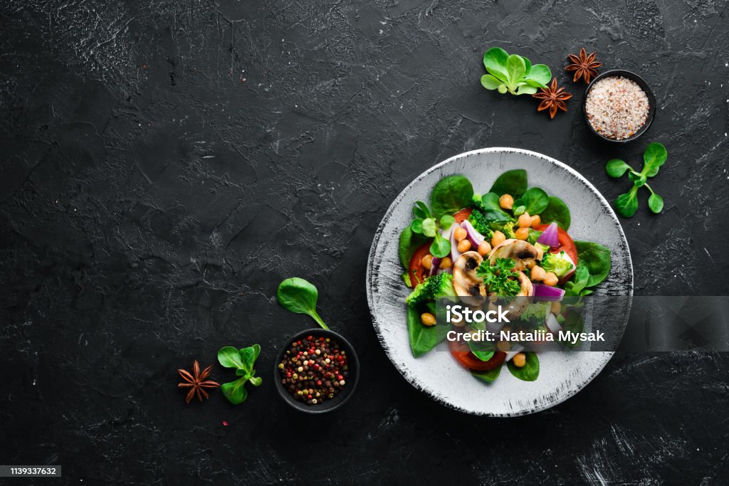 Salada com cogumelos, espinafre, ervilhas turcas e cebola em uma placa em um fundo de madeira vista superior. Espaço livre para o seu texto. Lisa Lopes - Foto de stock de Cogumelo - Fungo royalty-free