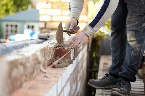 A bricklayer works on a new domestic kitchen extension using reclaimed bricks. Images show general construction and a cross section of the wall revealing insulation and outer and inner skins