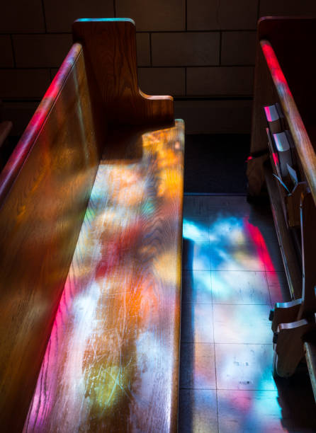 istock Light rays from stained glass window light up church aisle 1139342443