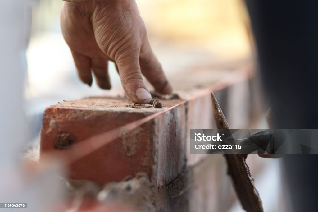 Bricklayer Building A New Extension With Reclaimed Bricks A bricklayer works on a new domestic kitchen extension using reclaimed bricks. Images show general construction and a cross section of the wall revealing insulation and outer and inner skins Construction Worker Stock Photo