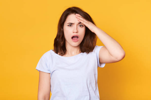 istock Portrait of forgetful female model remembers something, keeps hand on forehead, opens mouth with astonishment, remembers to do importent task, wears white casual t shirt. Bad memory concept. 1139344147