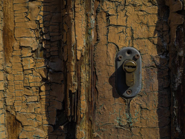 Vintage rustic door with a metallic lock and door handle. Detailed old wooden texture with chipped paint and a worn-out surface. Antique doorknob design. Backdrop for creative projects. Copy space