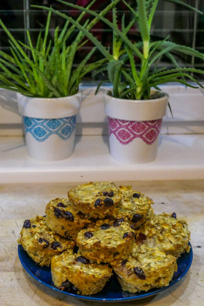 Homemade oat's muffins placed on a blue plate and a wooden chopping bard. In the back two aloes plants standing on a window ledge.  Healthy lifestyle with healthy snacks.