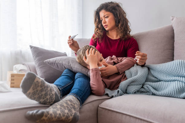 istock Young mother holding sick son child on hands, lying on knees, touching head measuring temperature 1139351973