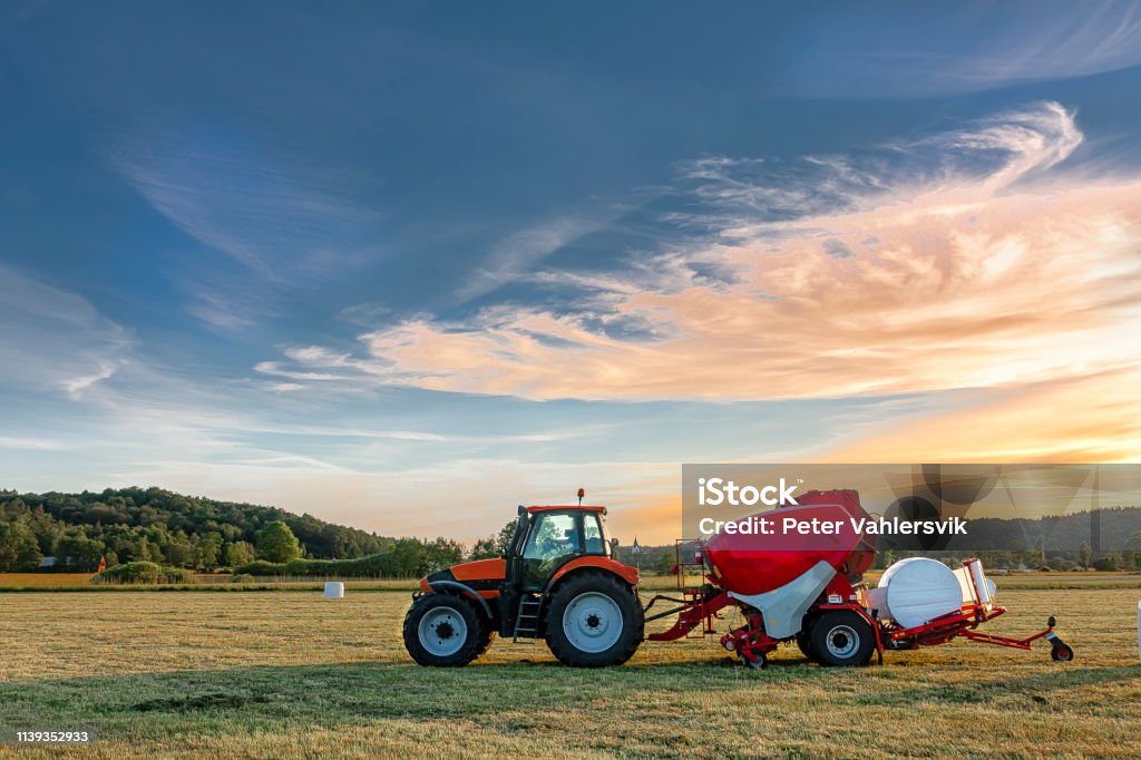 Tractor with silage bale machine Tractor with silage bale machine in rural landscape Tractor Stock Photo