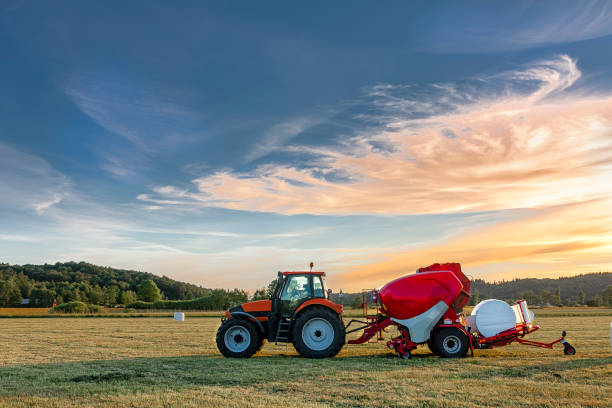 трактор с силосным тюков машины - silage field hay cultivated land стоковые фото и изображения