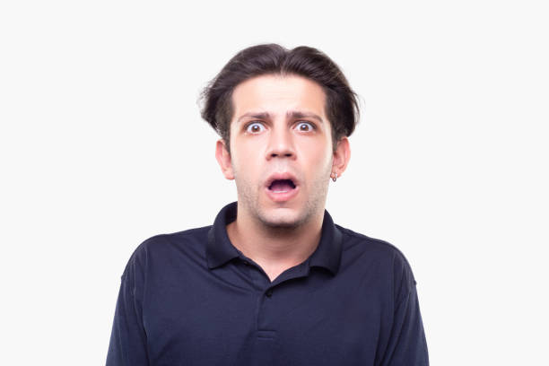 Portrait of a young man looking at camera with shocked facial expression over white background Portrait of a young man looking at camera with shocked facial expression over white background. Horizontal composition. Studio shot. confusion raised eyebrows human face men stock pictures, royalty-free photos & images