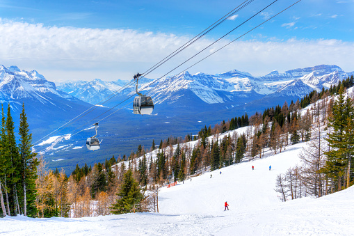 Skiing at Lake Louise in the Canadian Rockies of Alberta, Canada, with cable cars going up the mountains.