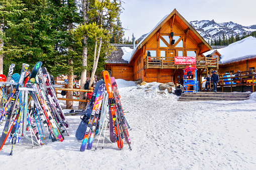 Colorful skis and snowboards line the rack outside the old and rustic Temple Lodge at Lake Louise in the back mountains of the Canadian Rockies of Alberta, Canada.