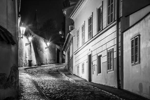 wąska brukowana ulica w starym średniowiecznym mieście z oświetlonymi domami przez zabytkowe lampy uliczne, novy svet, praga, czechy. nocny strzał - prague old door house zdjęcia i obrazy z banku zdjęć