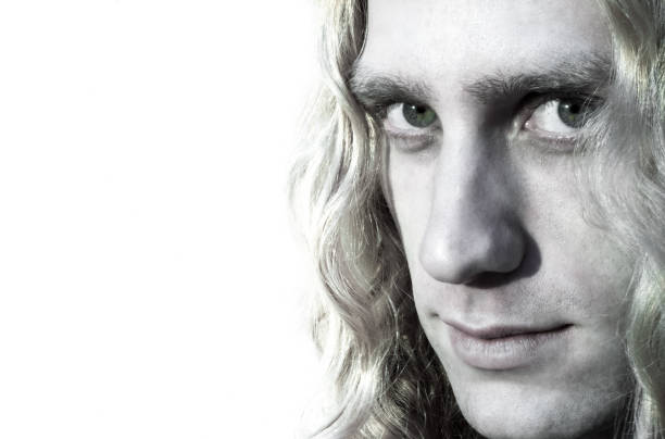 Young Man with Long Hair Looks Intently at Camera (Close-Up). Copy space available on the white background.
