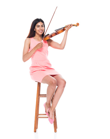 Attractive young latino female playing the violin while sitting on stool