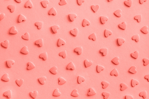 Love romantic pattern. Pink confectionery hearts sprinkles on pink, background, texture Coral toned