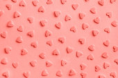 Love romantic pattern. Pink confectionery hearts sprinkles on pink, background, texture Coral toned